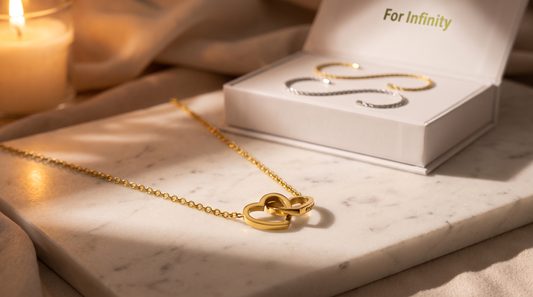 Engraved double heart necklace and permanent bracelet kit on white marble in warm light