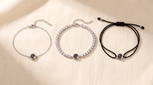 Chain, tennis, and cord bracelets each with a small lens charm on linen