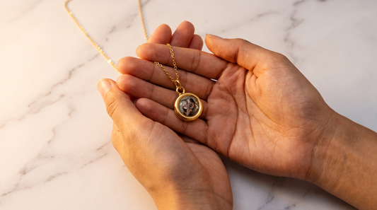 Circle Necklace with Picture Inside in gold held over white marble, the custom photo necklace with a hidden portrait inside
