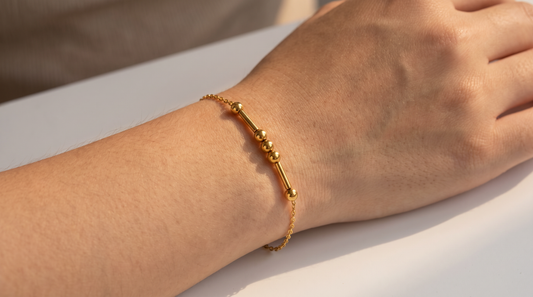 Gold Morse code bracelet on a woman's wrist with the dot and dash message pattern clearly visible