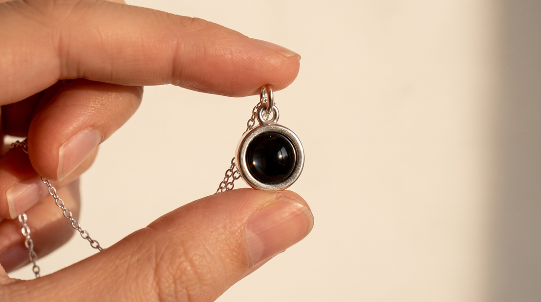 Circle lens pendant necklace held between two fingers