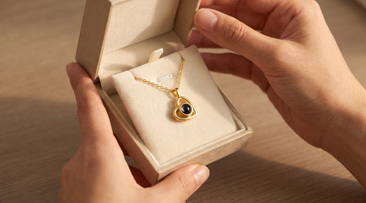 Hands opening a gift box revealing a gold heart pendant necklace