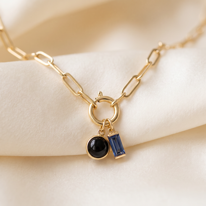 Close up of personalized birthstone charm necklace, gold paperclip chain with onyx and sapphire charm