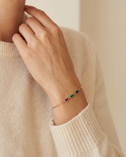 Woman wearing personalized dainty birthstone bracelet with ruby, emerald, and sapphire stones