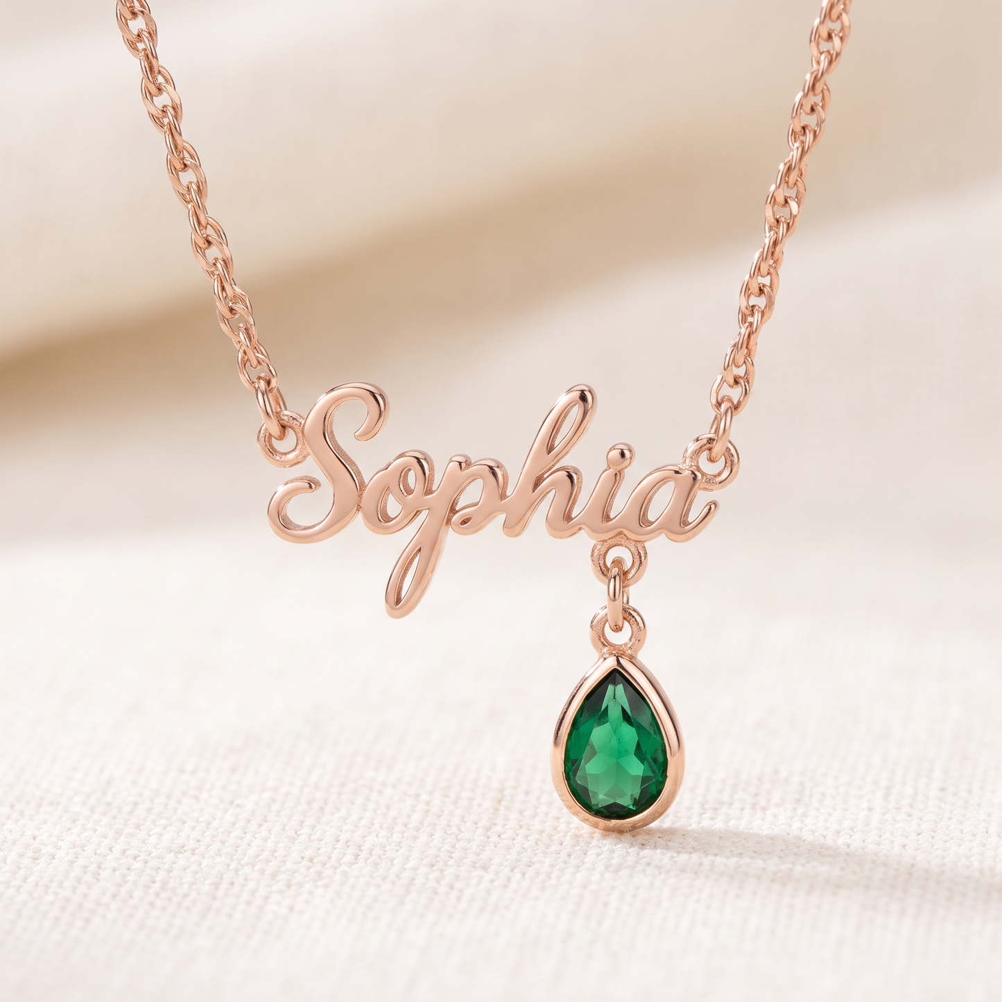Rose gold personalized name necklace with emerald birthstone charm close up