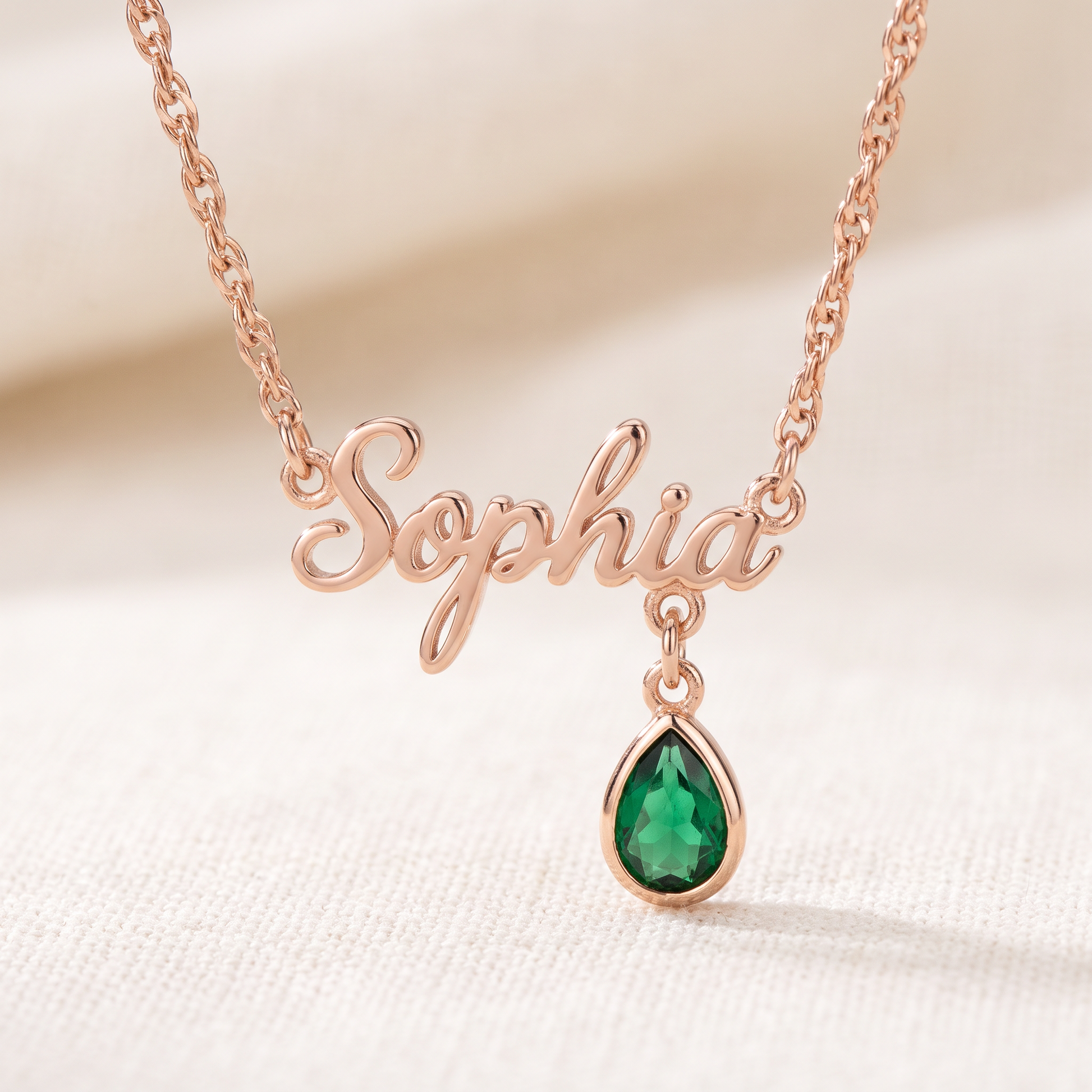 Rose gold personalized name necklace with emerald birthstone charm close up